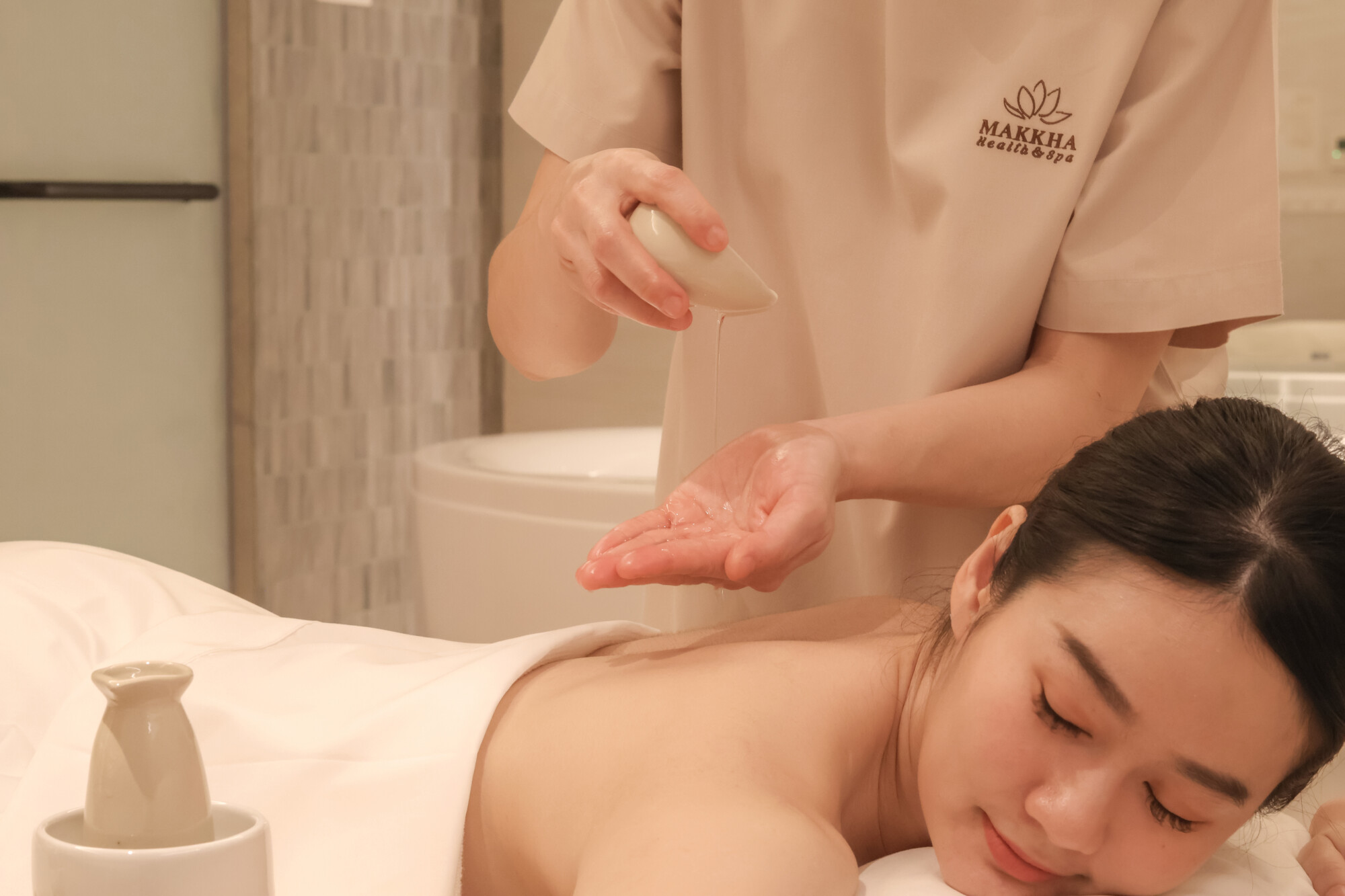 A therapist pouring oil on her hand during a massage