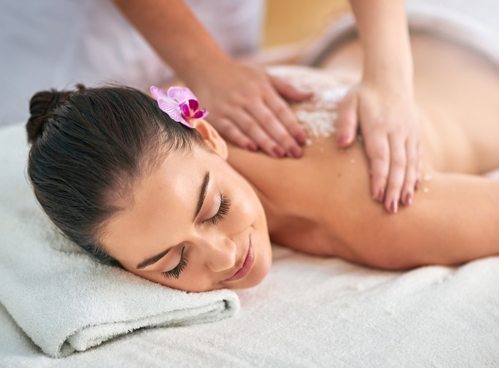 A woman enjoying a salt body scrub massage