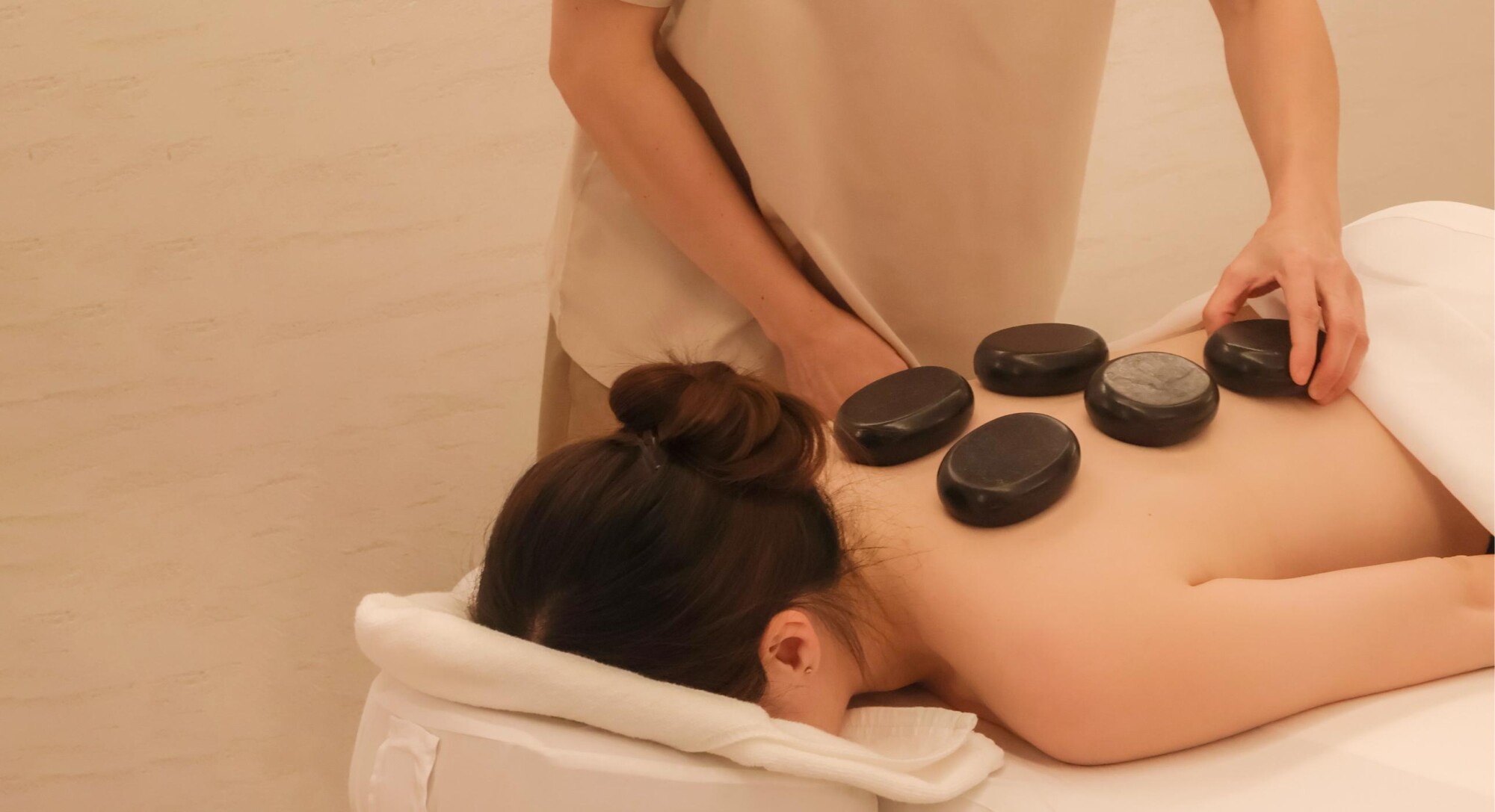 A therapist placing hot stones on a customer’s back